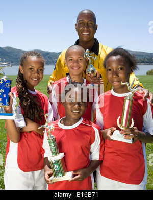 Multi-ethnic children holding soccer trophies Stock Photo