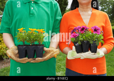 Senior Asian couple holding potted plants