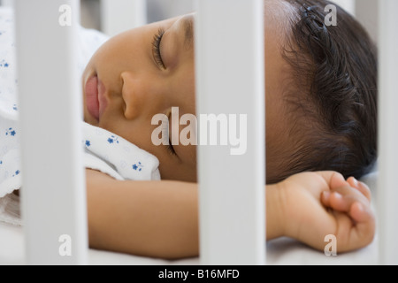 African American baby sleeping in crib Stock Photo