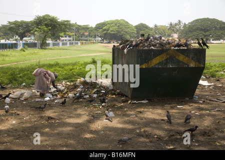 An elderly woman picks rags and recyclable items from a pile of rubbish in Mattancherry in Kochi, Kerala. Stock Photo