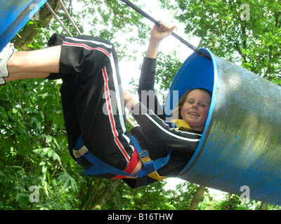 student climbing through barrel at school camp Stock Photo