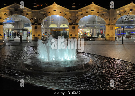 Sheffield Railway Station at night. People arriving by train and making their way throgh the forecourt and outside water feature Stock Photo