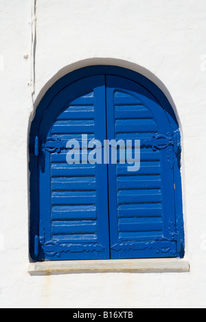 A shuttered window on a small church right next to the beach in Agios Sostis Tinos Greece Stock Photo