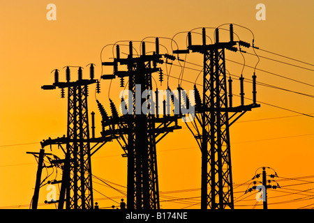 Energy Industry / Electricity. High voltage Transmission Towers silhouetted at sunset. Stock Photo