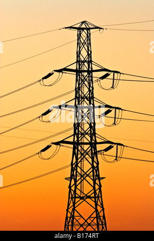 Energy Industry / High voltage Transmission Towers silhouetted at sunset. Stock Photo