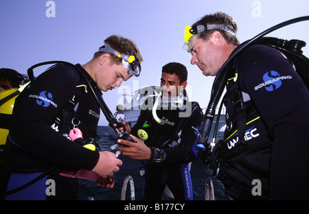 Dive guide briefing two divers. Hurgadha, Red Sea, Egypt. Stock Photo