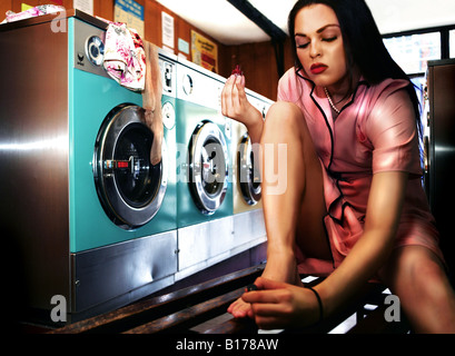 Woman paints her nails in launderette Stock Photo