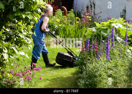 Woman Mowing Lawn in Summer Stock Photo