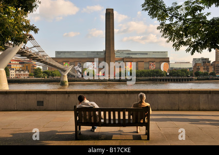 River Thames & Millennium Bridge with Tate Modern street art display on exterior walls refurbished redundant Bankside power station London England UK Stock Photo