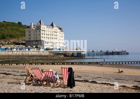 Seaside resort with red and white striped deckchairs on quiet North Beach with hotel on Welsh coast. Llandudno North Wales UK Stock Photo