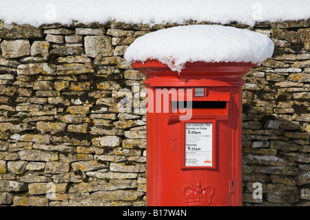red Royal Mail post box in snow by drystone wall Oxfordshire England UK Stock Photo