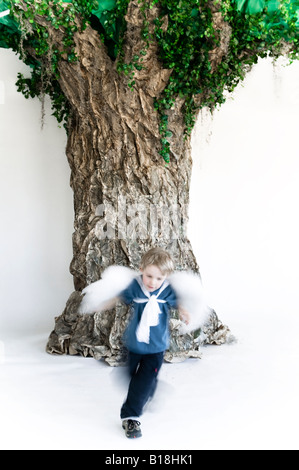 4 year old caucasian boy wearing angel wings running around a fake paper tree, Montreal, Quebec, Canada. Stock Photo