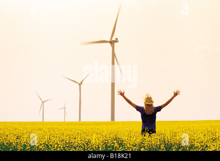 15 year old girl in canola field with wind turbines in the background, St. Leon, Manitoba, Canada Stock Photo