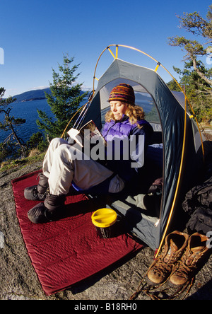 Woman reads a book in her tent, Lighthouse Park, West Vancouver, British Columbia, Canada. Stock Photo