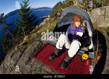 Woman reads a book in her tent, Lighthouse Park, West Vancouver, British Columbia, Canada. Stock Photo