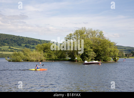Man kayaking past the crannog or man made island in Llangorse Lake Wales UK Stock Photo