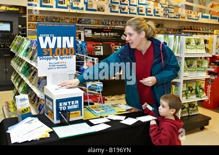 EVENTS Algonquin Illinois Woman with young boy place sweepstakes entry form in box at OfficeMax retail store grand opening Stock Photo