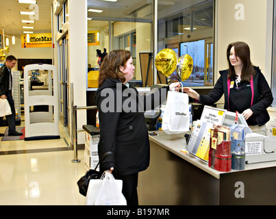 EVENTS Algonquin Illinois Woman make purchase at checkout counter in OfficeMax retail store salesclerk hand bags to customer Stock Photo