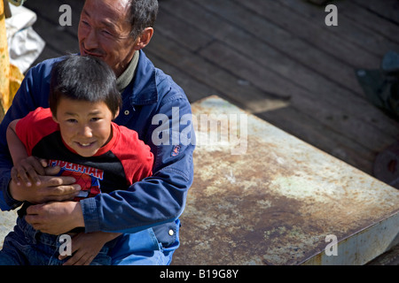 Greenland, Ilulissat. A father of Inuit extraction plays with his son on the deck of a fishing boat in the port area. Stock Photo