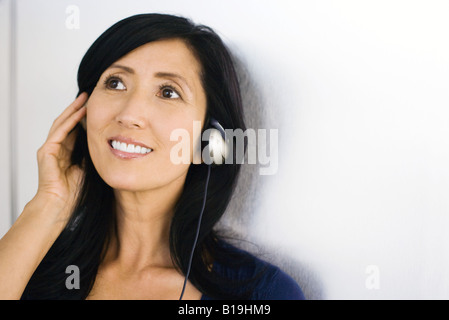 Woman listening to headphones, smiling Stock Photo
