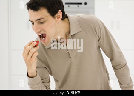 Man eating strawberry, mouth open Stock Photo