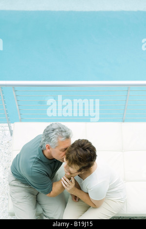 Couple sitting on balcony, man kissing woman's cheek, high angle view Stock Photo