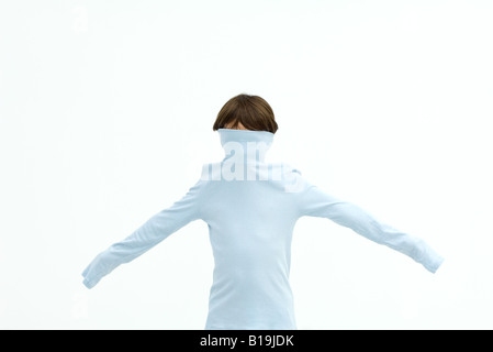 Boy wearing turtleneck pulled over his face, arms outstretched Stock Photo