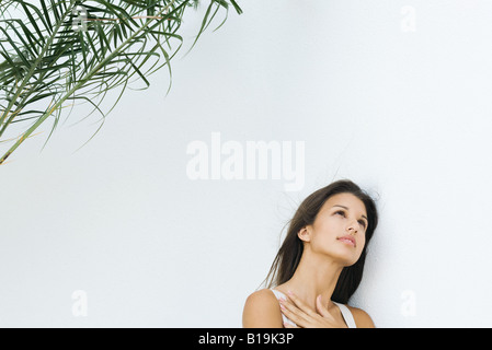 Teen girl leaning against wall with hand on chest, looking up Teen girl leaning against wall with hand on chest, looking up