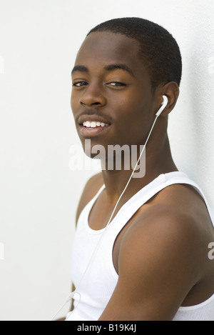 Teen boy listening to earphones, smiling at camera, portrait Stock Photo