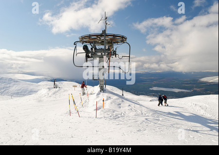 Snow-boarder arriving on ski lift at the summit of the Aviemore in the Cairngorms Scotland with views of the surrounding area Stock Photo