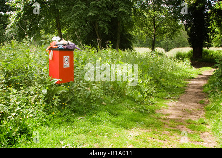 Very smelly and overflowing dog bin next to a footpath in the countryside Stock Photo