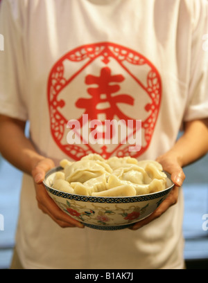 Chinese young woman holding a bowl of Chinese dumpling Stock Photo