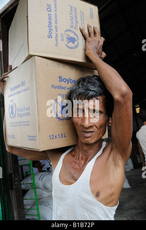 A man carries boxes of soybean oil donated by United Nations World Food Programme WFP to people affected by Cyclone Nargis in Myanmar Stock Photo