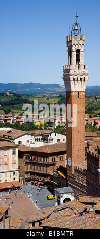 Aerial vertical Panorama 12th century Piazza Del Campo walled city Siena Italy belltower clear blue sky green mountains modern buildings in background Stock Photo