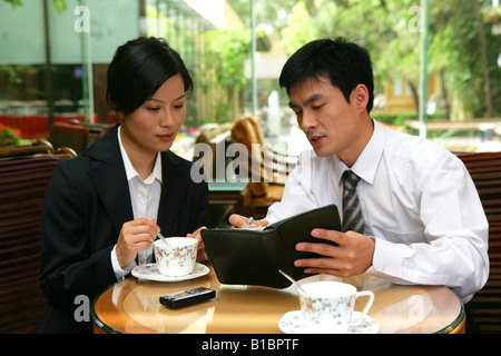 businessman and businesswoman drinking coffee and talking at hotel hall Stock Photo