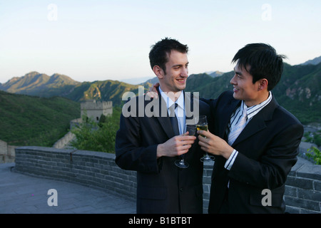 Chinese businessman and caucasian businessman talking with wineglasses on Great Wall,Beijing,China Stock Photo