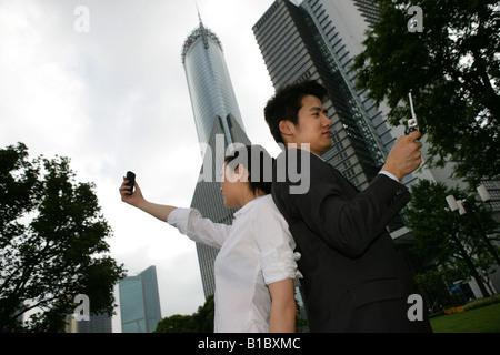 businessman and businesswoman taking pictures with camera phone outside office building in Pudong,Shanghai,China Stock Photo