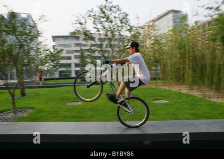 young man performing a stunt with a bicycle on square beside office buildings,Beijing,China Stock Photo