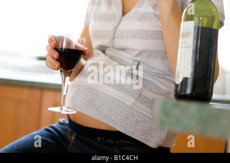 Worried looking pregnant woman drinking wine Stock Photo