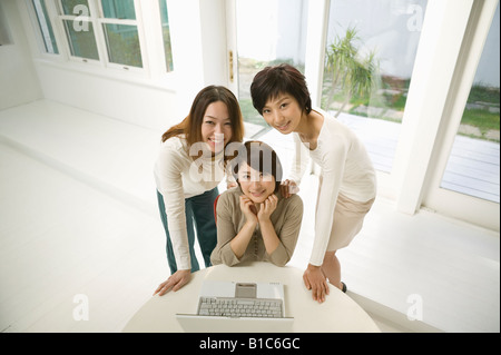 young Asian woman using laptop computer sitting on living room couch ...