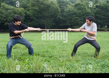 Two young men pulling rope Stock Photo