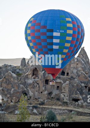 Flying Low. A tourist hot air balloon flight flies low in front of Fairy Chimney cave dwellings characteristic of this region Stock Photo