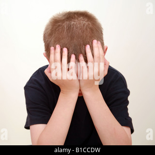 Boy in studio with hands over face crying Stock Photo