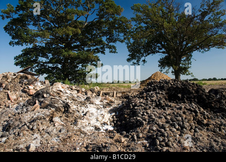 Heaps of burnt produce and rubbish on farmland. Stock Photo