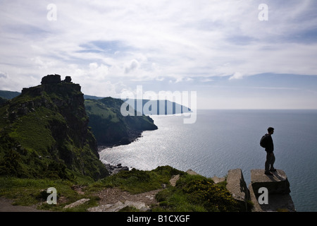 Walker admiring the view from the cliff edge at the Valley of Rocks (Castle Rock behind), near Lynton, Exmoor, Devon Stock Photo