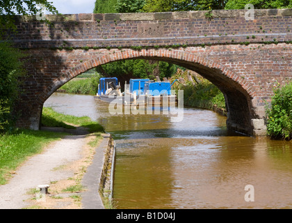 British Waterways Work Barges Moored on the Trent and Mersey Canal near Bridge at Rode Heath Cheshire England United Kingdom UK Stock Photo