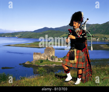 Scottish Bagpiper on hill above Eilean Donan Castle Scotland Stock ...