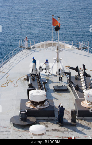 Washing the anchor chain as it is winched in on Cunard QE2 Deck hand indicates how much further to go while officer watches Stock Photo