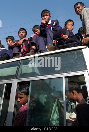 Indian schoolboys on a bus roof seen through window of neighboring bus ...