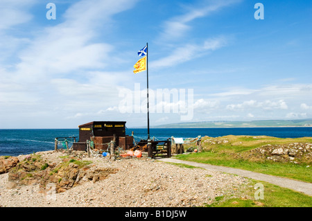 A Lion Rampant and a Scottish Saltire flag fly above the Macrahanish sea bird centre on the South West of Scotland. Stock Photo